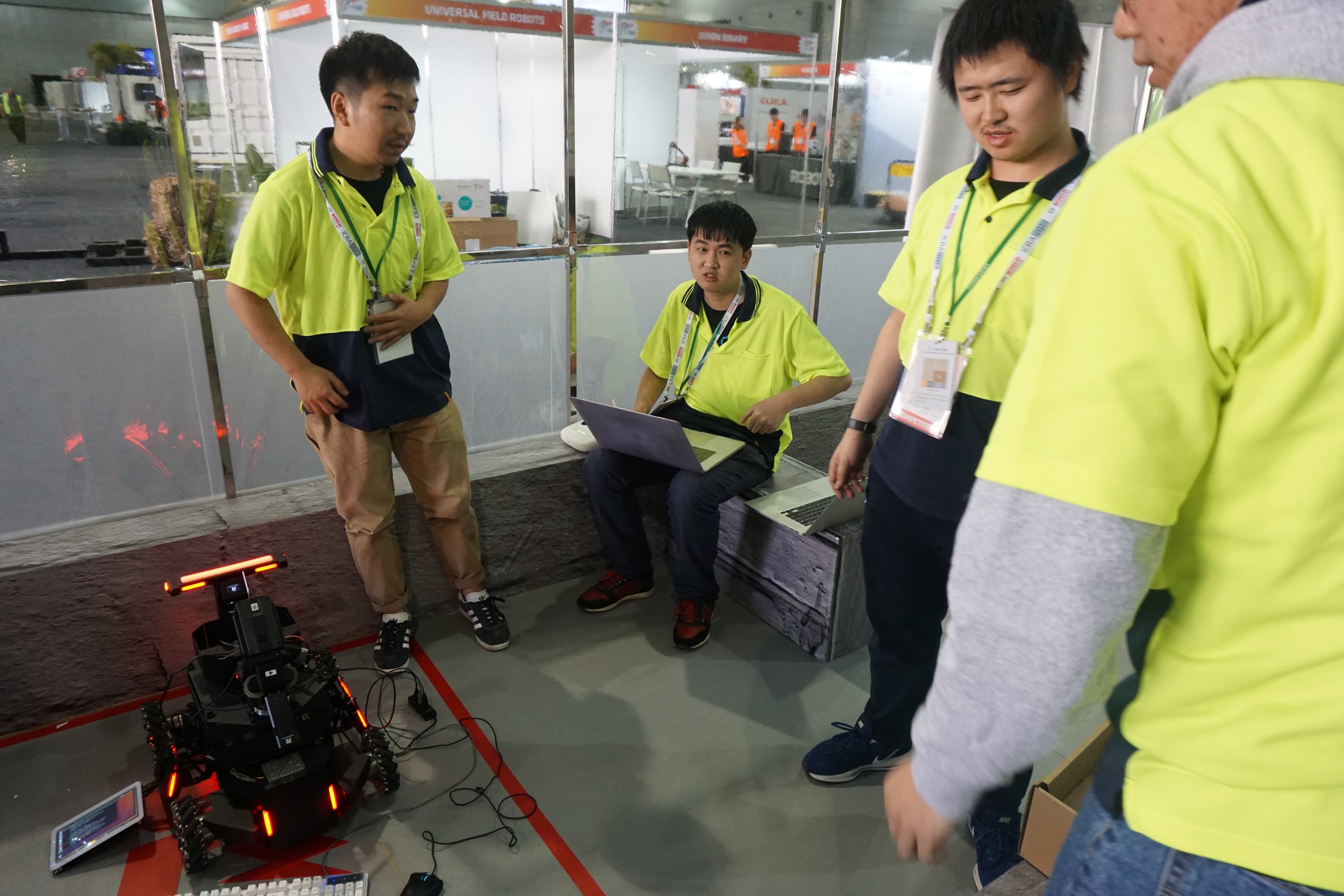 Team members using laptops beside the robot at the competition field