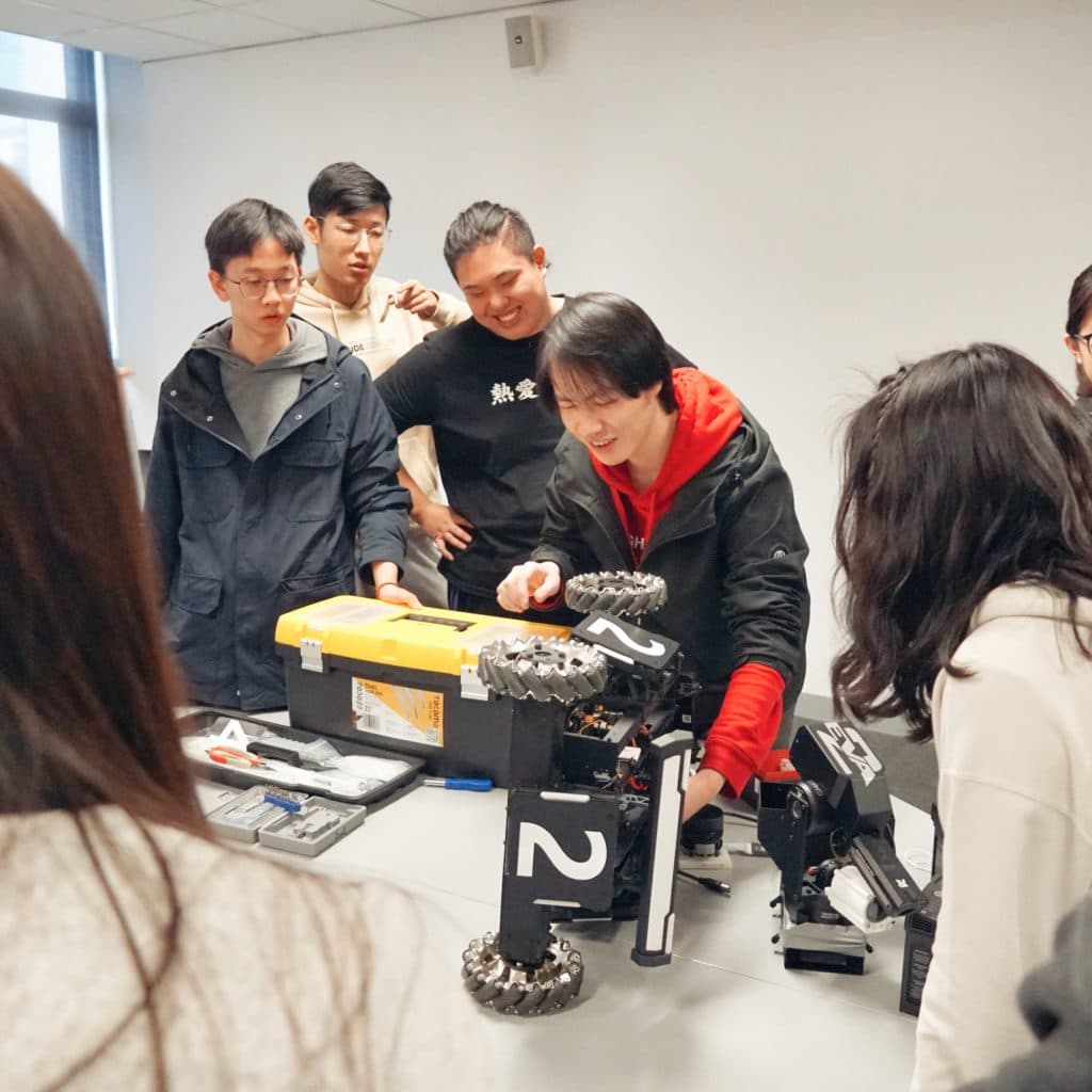 Workshop participants gathered around a robot during a hardware demonstration